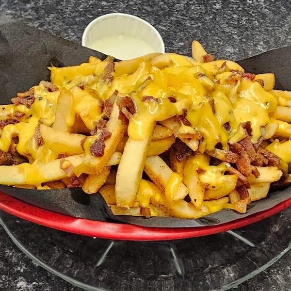 Rock & Roll Diner's cheesy bacon fries in a red basket with a side of ranch.