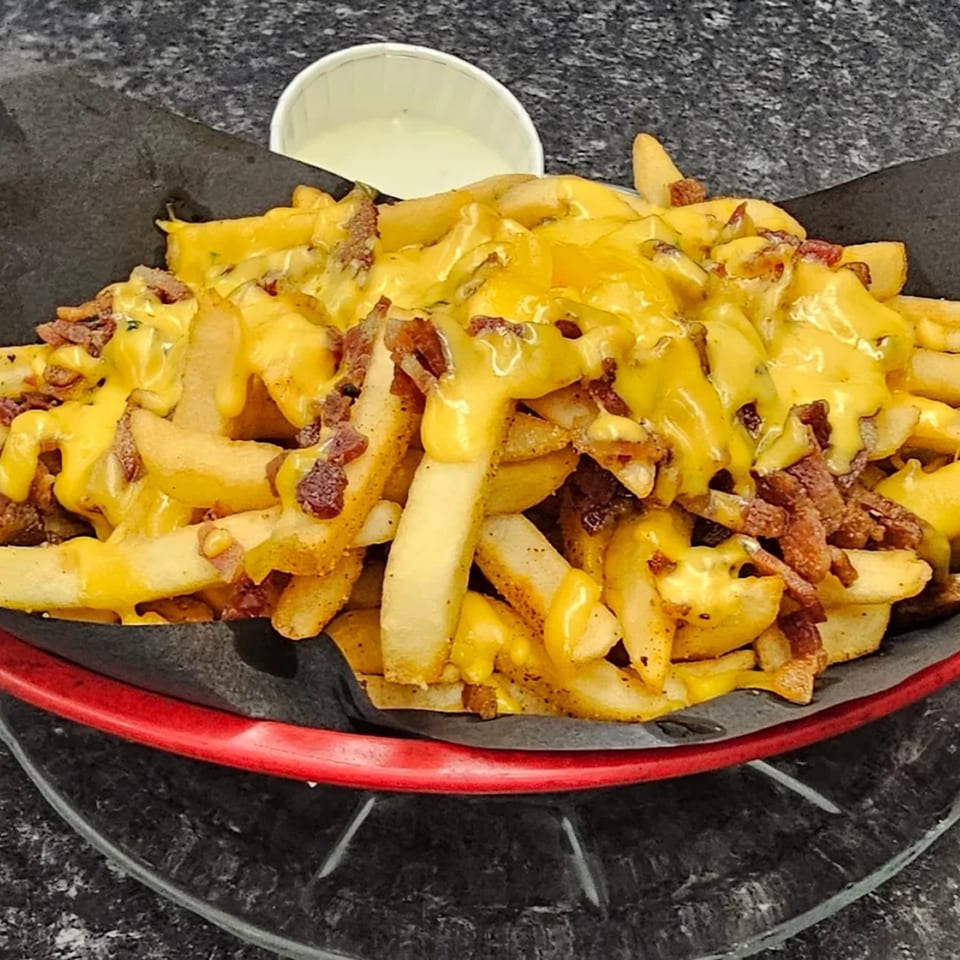 Rock & Roll Diner's cheesy bacon fries in a red basket with a side of ranch.