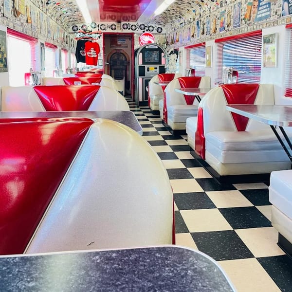Interior of Rock & Roll Diner with red and white booths, checkered floor, and a jukebox.